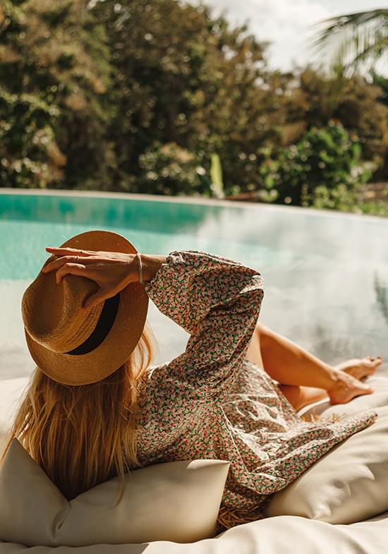 Woman sitting by pool with sunhat